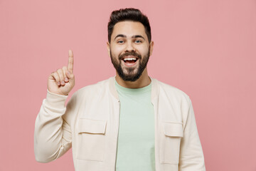 Young smiling happy caucasian man 20s wearing trendy jacket shirt holding index finger up with great new idea isolated on plain pastel light pink background studio portrait. People lifestyle concept.