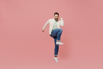 Fototapeta na wymiar Full body young smiling happy man 20s wearing trendy jacket shirt do winner gesture clench fist raise up leg isolated on plain pastel light pink background studio portrait. People lifestyle concept.