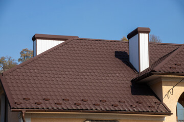 The roof of the house is made of red metal tiles, a beautiful large chimney