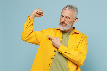 Elderly gray-haired mustache bearded man 50s in yellow shirt point finger on biceps muscles on hand...