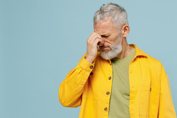 Elderly thoughtful gray-haired mustache bearded man 50s wear yellow shirt keep eyes closed rub put hand on nose isolated on plain pastel light blue background studio portrait People lifestyle concept