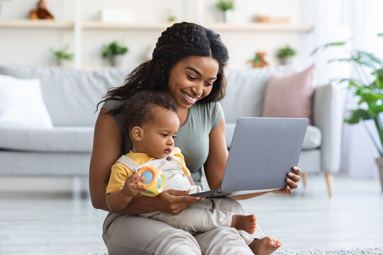 Happy Black Mother And Little Infant Son Using Laptop Computer At Home