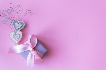 gift box with bow on pink background with hearts. Flat lay, top view, copy space.
