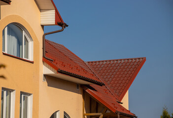 The roof of the house is made of red metal tiles, a beautiful large chimney