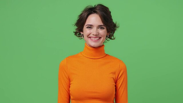 Happy stunning delight fascinating young brunette woman 20s years old wears orange shirt looking camera smiling isolated on plain green background studio portrait. People emotions lifestyle concept