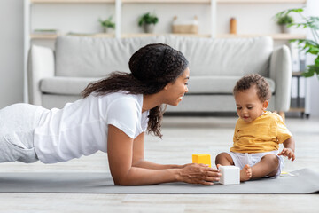 Healthy Lifestyle Concept. Young Black Mother Training At Home With Little Baby