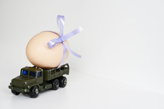 A mini truck toy is transporting an egg for Easter, next to place for text.
