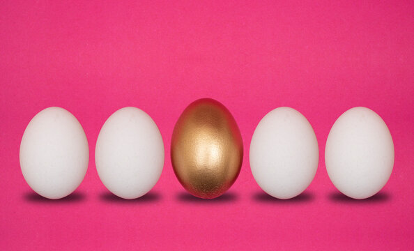 Concept of individuality, choices. One golden egg with white eggs pink background