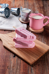 Various yogurt popsicles with strawberry. One of them is bitten, missing a piece. Copy space.