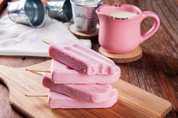 Various yogurt popsicles with strawberry. One of them is bitten, missing a piece. Copy space.