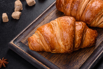 Delicious fresh crispy croissants on a dark concrete background. Tasty breakfast