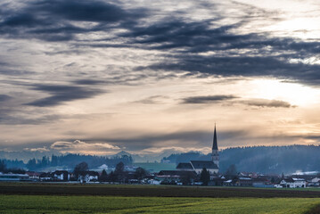 Fototapeta na wymiar Alpen Panorama mit Kirche, am Abend mit dramatischen Wolken Bergen im Chiemgau, 