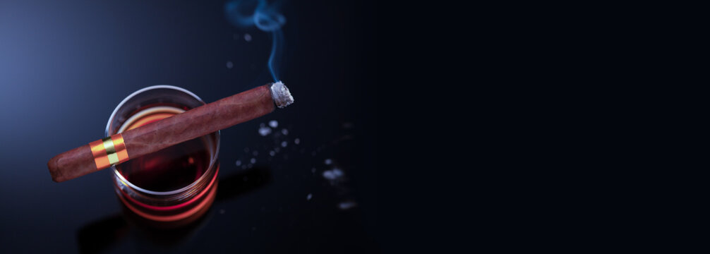 Brennende Zigarre liegt auf einem Glas mit Whiskey und raucht, Perspektive von oben