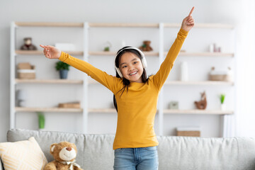 Beautiful little asian girl listening to music and dancing