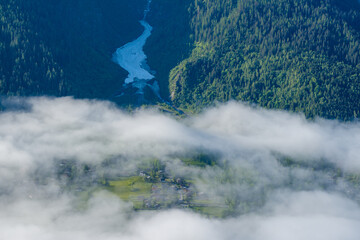 A snowfall between mountains and lush green forests in the Mont Blanc massif in Europe, France, the Alps, towards Chamonix, in summer, on a sunny day.