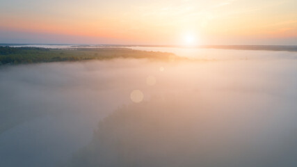 Summer dawn over foggy forest and river aerial drone view