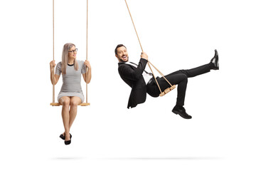 Businessman and a young woman sitting on swings - obrazy, fototapety, plakaty