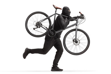 Man in black clothes and balaclava stealing a bicycle and running - obrazy, fototapety, plakaty