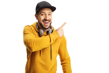 Cheerful guy with headphones and a cap pointing to the side