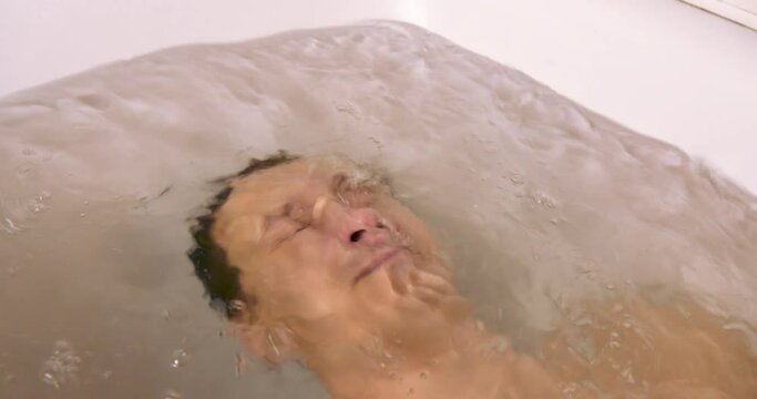 Young Man Lies Underwater in the Bath. Depression Concept and Emotional Instability. Open Eyes and Bubbles from the Mouth of Dived Man. Breath Holding