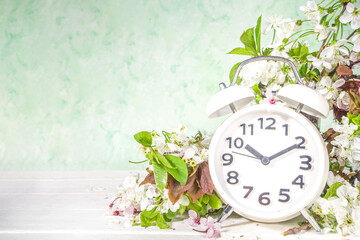 Spring Forward Time, Savings Daylight Concept with Alarm Clock and Spring Garden Flowers on wooden...