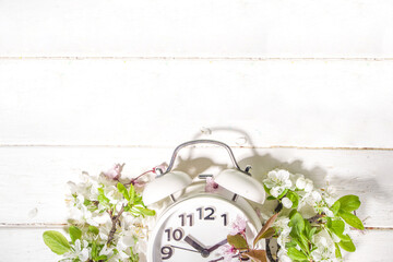 Spring Forward Time, Savings Daylight Concept with Alarm Clock and Spring Garden Flowers on wooden...