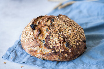 Sourdough bread with raisins and oats on a blue napkin on a gray background.