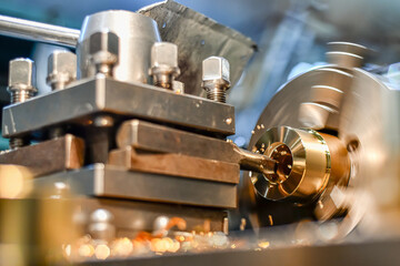 Manufacturing of a part from bronze on a lathe. Non-ferrous metal cutting. - obrazy, fototapety, plakaty