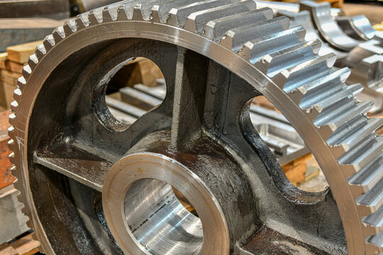 The cogwheel, after being manufactured on a cnc machine, lies on a wooden rack in a warehouse in a factory.