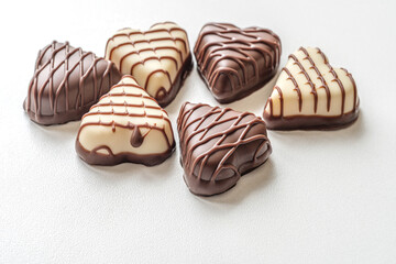 dark and white chocolate candies in the shape of hearts on a white surface