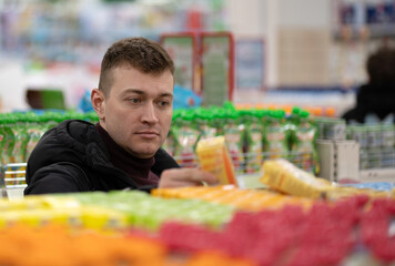 a man chooses baby food for his child in a store.