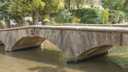 Old English stone bridge crossing a shallow river
