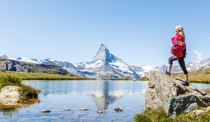 Woman on mountain top of mountain landscape around lake and blue sky.