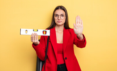 pretty woman looking serious showing open palm making stop gesture. architect with a level