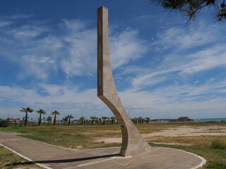 modern sundial built by light stones along the promenade of Termoli with a green lawn and the blue sea in the background