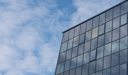 Fototapeta na wymiar Photo of a building with glass windows in the city against a blue sky with white clouds