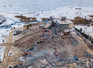 Heavy equipment being used to tear tearing down building construction. Excavator working on a demolition site. Drone view 