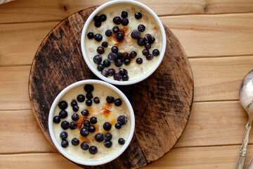 Baked porridge with cream and blueberries. Top view, wooden background