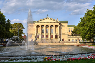 a fountain, flower beds and the facade of the historic opera house