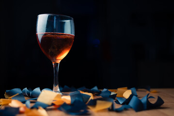 glass of red sparkling wine on black background with candy