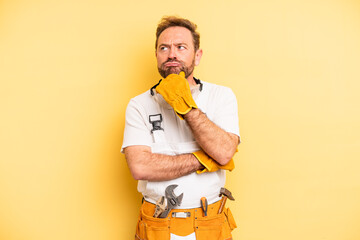 middle age man thinking, feeling doubtful and confused. handyman and repair concept