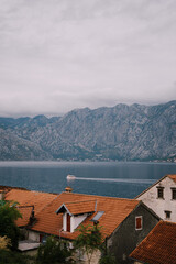 Boat sails along the bay against the backdrop of mountains on a cloudy day