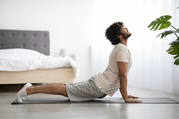 Fototapeta Happy athletic indian man stretching his body at home obraz