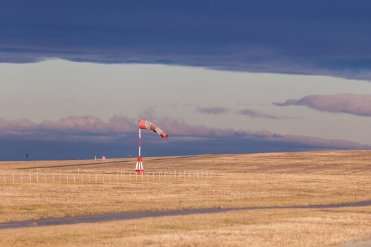 Windsock showing strong winds with dark clouds at an airport
