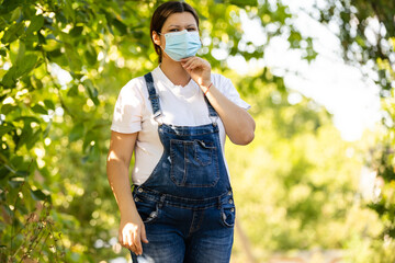 Young pregnant woman in protective medical mask covered her face. Virus protection and hygiene.