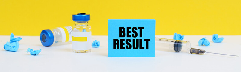 On the table is a syringe, injections and a blue sign with the inscription - BEST RESULT