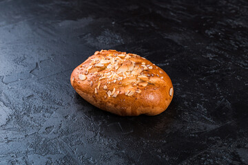 Freshly baked tasty bun on a dark table. Tasty baked goods straight from the bakery. Black background.