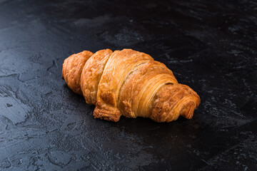 Fresh croissant on a black slate background. Copy space