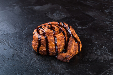 Freshly baked tasty bun on a dark table. Tasty baked goods straight from the bakery. Black background.