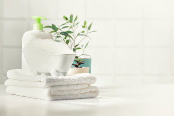 A miniature bubble bath, shampoo, flowers and white towels on bathroom countertop